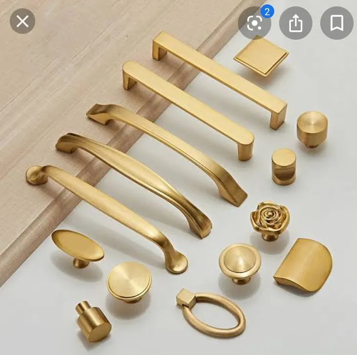 This may contain: various brass handles and knobs on a white surface, including one door handle with a rosette in the middle